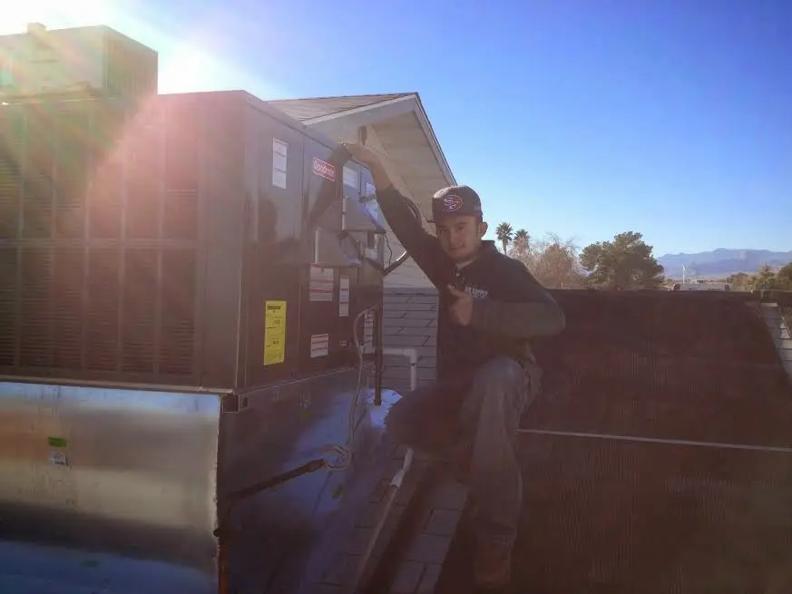 HVAC technician performing AC Tune-Up on a rooftop unit in Medway