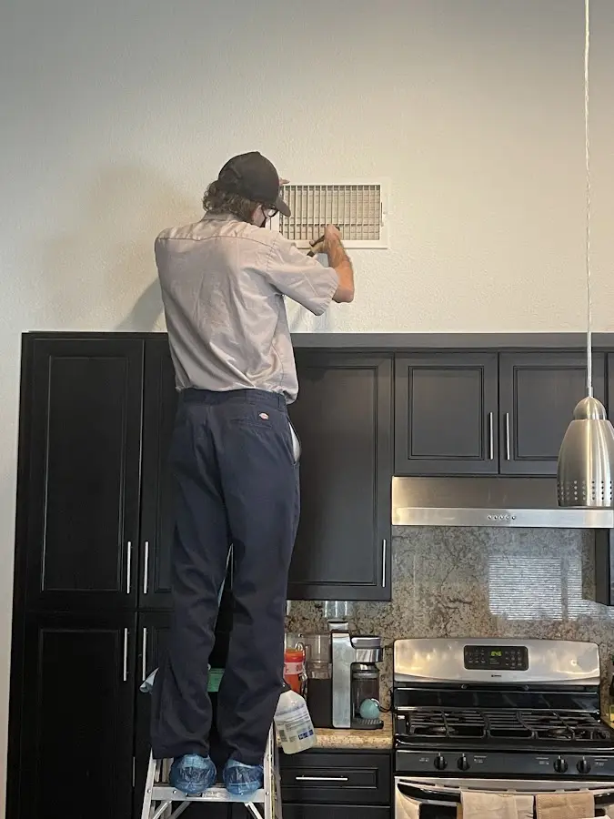 Technician inspecting an air vent during HVAC service in Medway